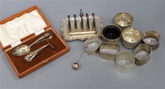 A cased silver spoon and pusher, a silver toast rack, three silver salts, five silver napkin rings and a silver salt spoon.